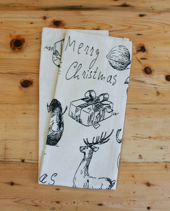 Folded tea towel with Christmas-themed designs on a wooden surface