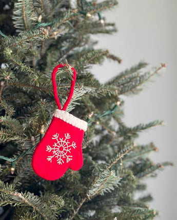 Red mitten ornament with a snowflake design on a Christmas tree.
