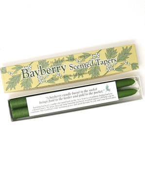 A pair of green bayberry scented taper candles in a gift box with holiday-themed decoration