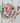 Napkin with strawberry pattern on a stack of plates with wooden cutlery on a white wooden surface