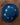 Blue woven hat with floral embellishments on a wooden surface