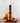 Bottle of Maple Wood Smoked Onion Hot Sauce with an onion and peppers on a wooden surface.