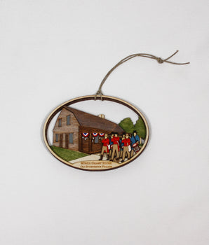 Decorative ornament with a scene of the Miner Grant Store and a fife and drum parade on a white background