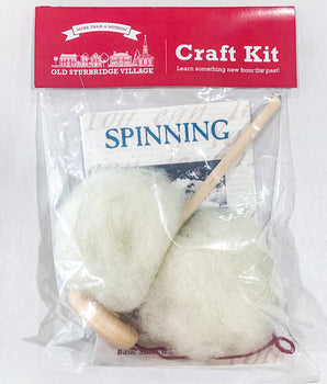 Packaged spinning craft kit with a drop spindle and white roving displayed in front of a red label that reads 'SPINNING'.
