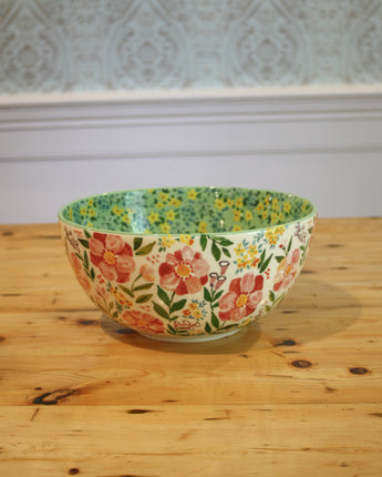 Decorative floral-patterned bowl on a wooden surface with a white wall in the background