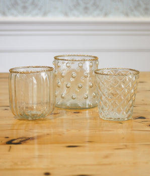 Three glass candle holders with textured designs on a wooden surface.