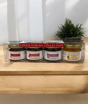 Four jars of Preserves on a wooden surface with a plant in the background