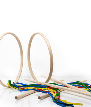 Two wooden hoops and several birch wands with multicolored ribbons laid out on a white surface.