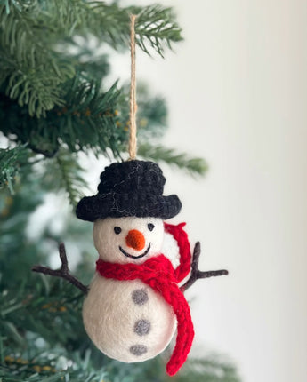 Felt snowman ornament with a black top hat and red scarf hanging on a Christmas tree.